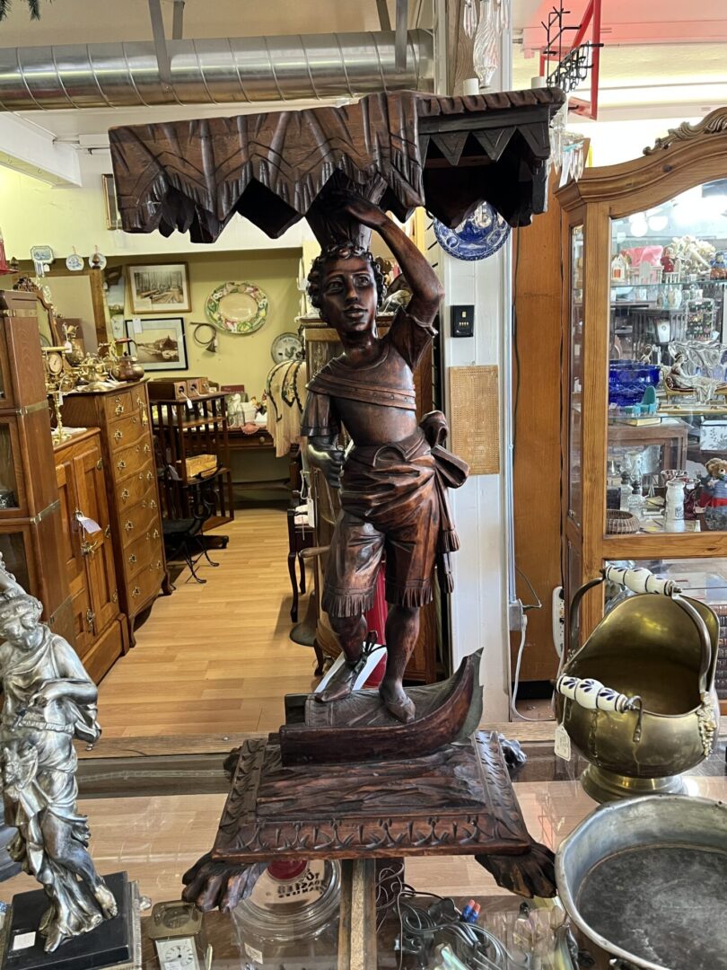 Intricately carved wooden statue of a warrior in a vintage shop.